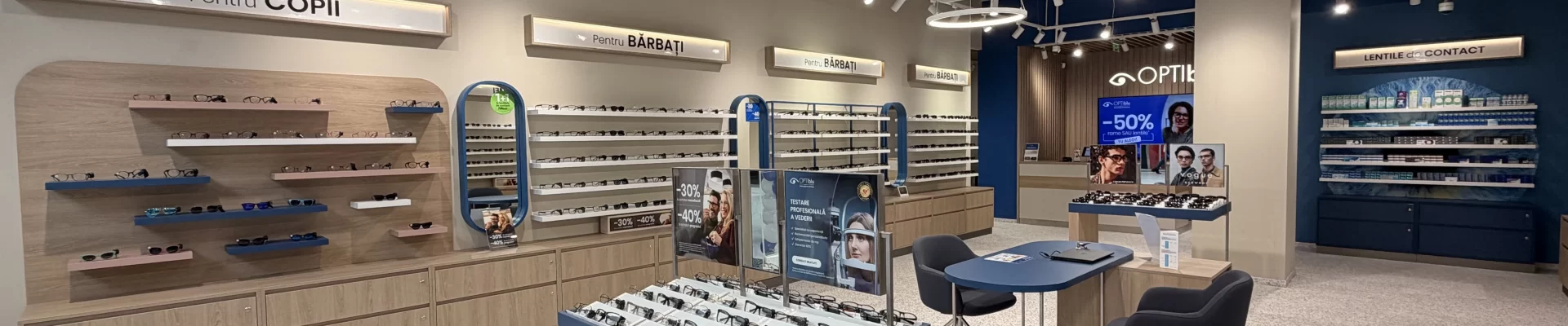 Interiorul magazinului OPTIblu din Târgoviște, cu rame de ochelari expuse și o zonă de consiliere pentru clienți.