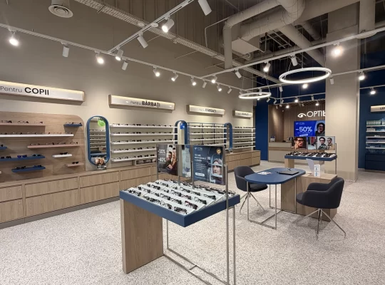 Interiorul magazinului OPTIblu din Târgoviște, cu rame de ochelari expuse și o zonă de consiliere pentru clienți.